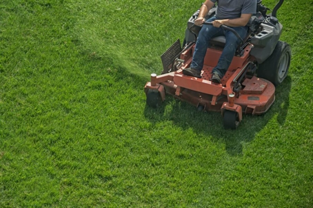 Man sitting on lawn mower mowing lawn.